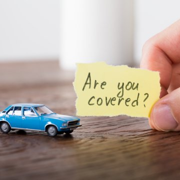 toco warranty overview vehicle service contract hand holding piece of paper that says are you covered blue toy car on table